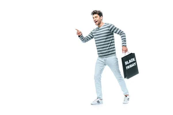 Homme émotionnel pointant et tenant sac à provisions le vendredi noir, isolé sur blanc — Photo de stock