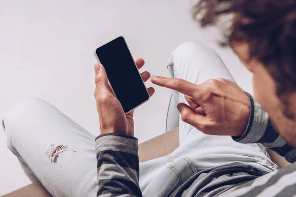 Vista recortada del hombre utilizando un teléfono inteligente con pantalla en blanco aislado en gris - foto de stock