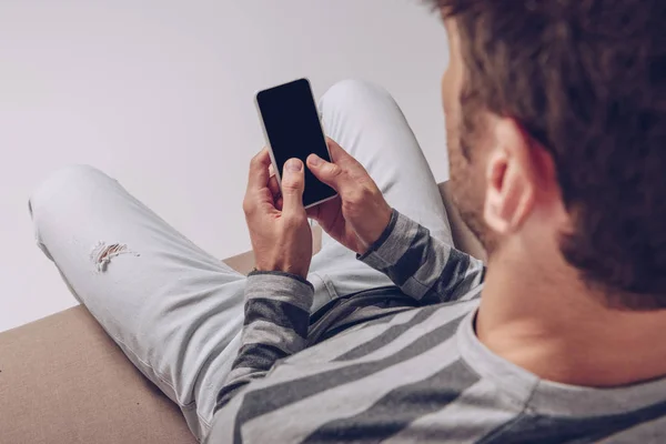 Vista recortada del hombre utilizando un teléfono inteligente con pantalla en blanco aislado en gris - foto de stock