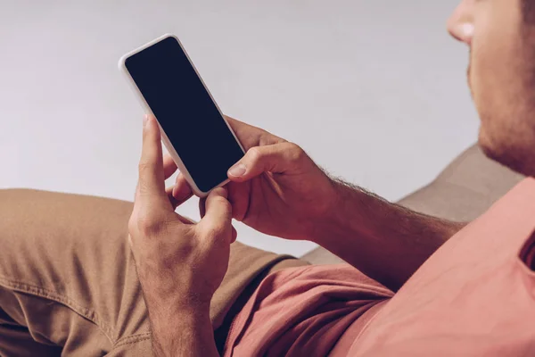 Vista parcial del hombre usando smartphone con pantalla en blanco aislada en gris - foto de stock