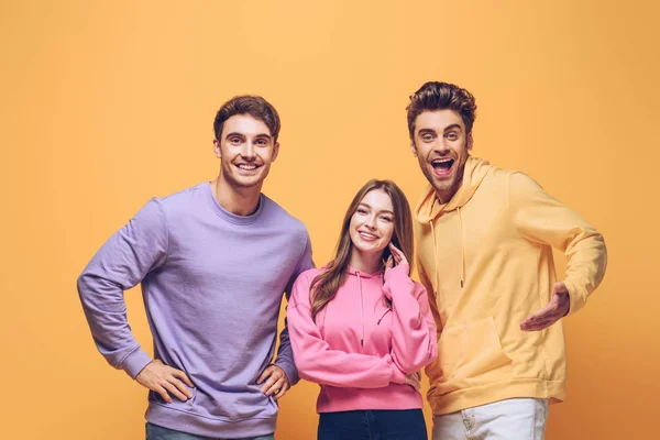 Smiling friends standing together, isolated on yellow — Stock Photo