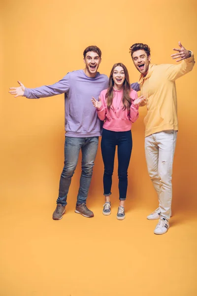 Happy emotional friends standing together, isolated on yellow — Stock Photo