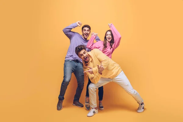 Excited friends having fun together, on yellow — Stock Photo