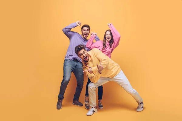 Amigos emocionados divirtiéndose juntos, en amarillo - foto de stock