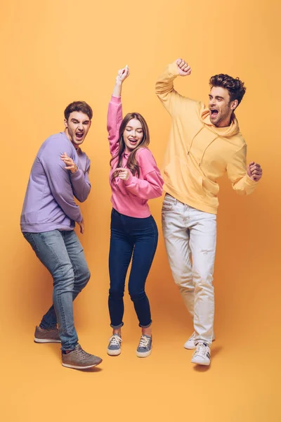 Young excited friends having fun together, on yellow — Stock Photo