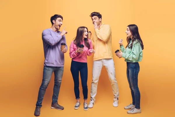 Amigos rindo fofocas e segurando café para ir, em amarelo — Fotografia de Stock