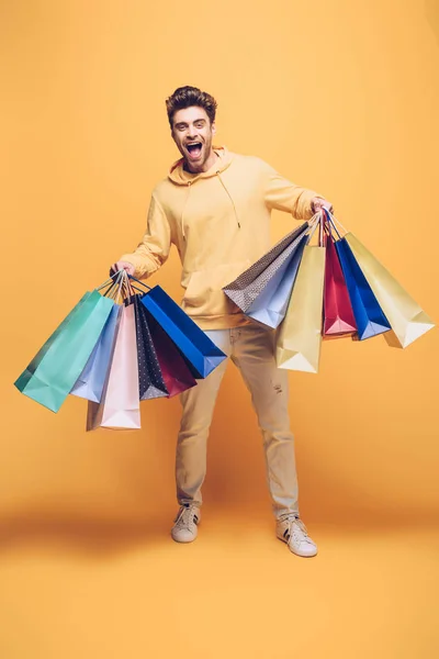 Excited man holding shopping bag, on yellow — Stock Photo