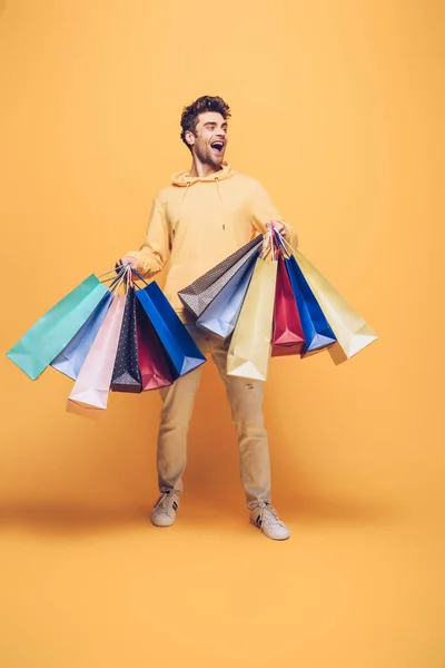 Uomo sorpreso in possesso di shopping bag, sul giallo — Foto stock