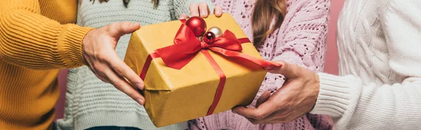 Cropped view of friends gifting christmas gift to you, isolated on pink — Stock Photo