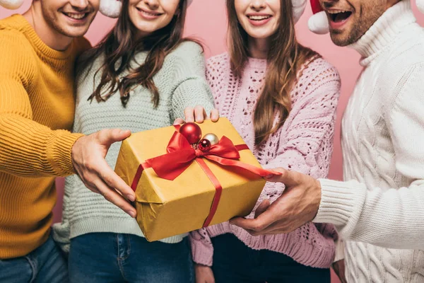 Vista recortada de amigos regalando navidad presente a usted, aislado en rosa - foto de stock