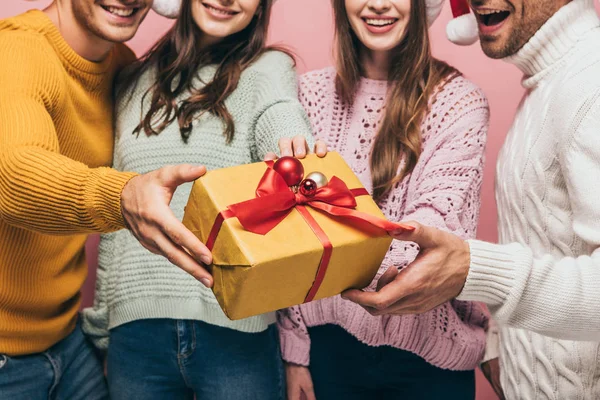 Cropped view of friends gifting christmas present to you, isolated on pink — Stock Photo