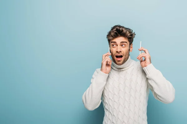 Homme confus parlant sur deux smartphones, isolé sur bleu — Photo de stock