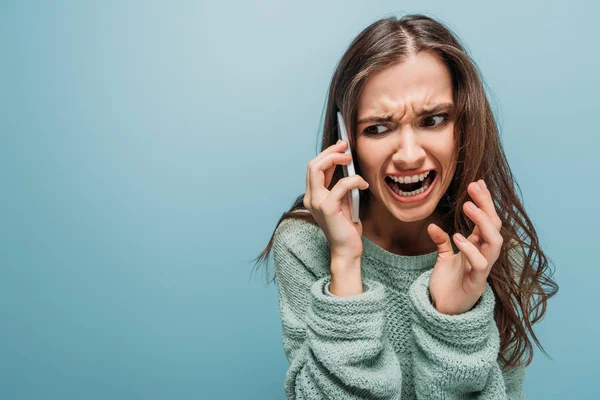 Mujer agresiva gritando y hablando en el teléfono inteligente, aislado en azul - foto de stock