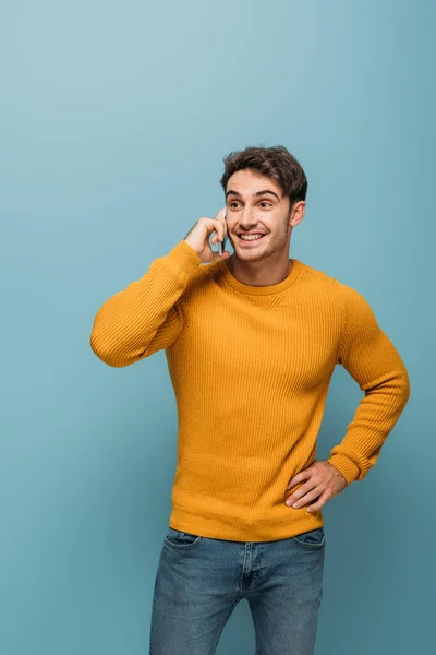 Schöner lächelnder Mann, der auf dem Smartphone spricht, isoliert auf blauem Grund — Stockfoto
