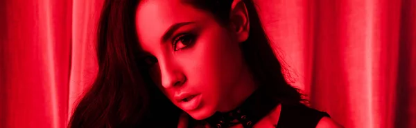 Панорамный снимок красивой страстной молодой женщины, позирующей в красном свете — стоковое фото