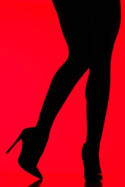 Silhouette of sexy woman in heels posing on red — Stock Photo