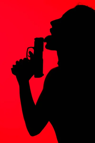Silhouette of criminal seductive woman licking gun isolated on red — Stock Photo