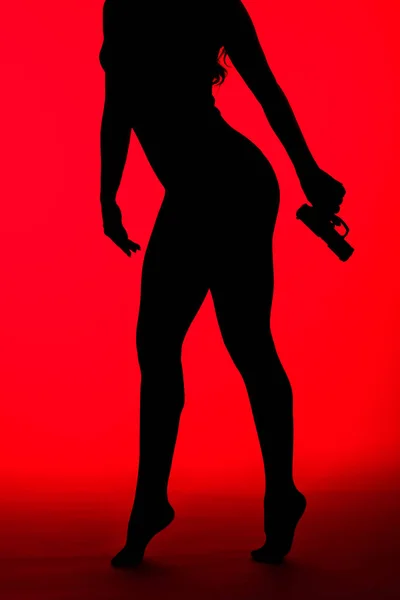 Silueta de criminal sexy mujer sosteniendo arma aislada en rojo - foto de stock