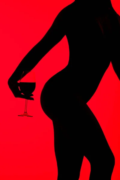 Ausgeschnittene Ansicht der schwarzen Silhouette des verführerischen Mädchens mit einem Glas Wein auf Rot — Stockfoto