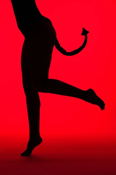 Cropped view of silhouette of sexy girl in Devil costume, isolated on red — Stock Photo