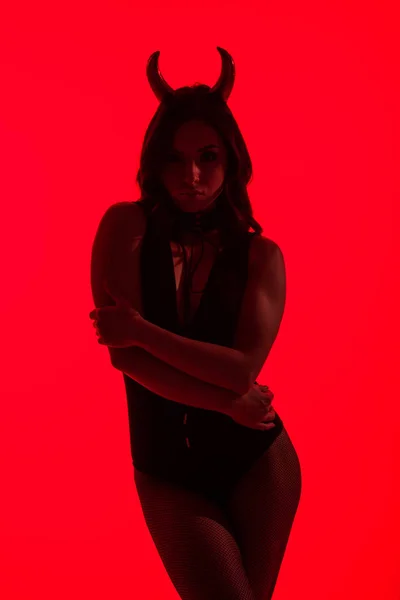 Silueta de mujer sexy en traje de diablo, aislado en rojo - foto de stock