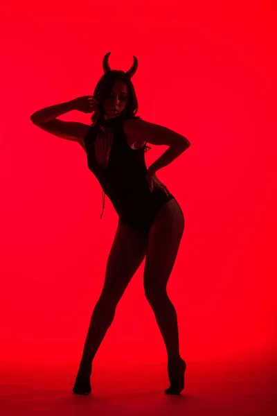 Силуэт страстной женщины в костюме Дьявола, изолированный на красном — стоковое фото