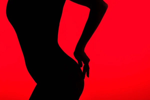 Silueta negra de hermosas nalgas de chica seductora, aislada en rojo - foto de stock