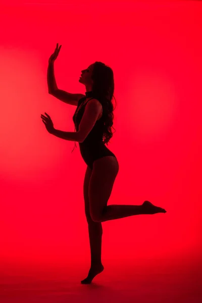 Silhouette of elegant sexy young woman, isolated on red — Stock Photo