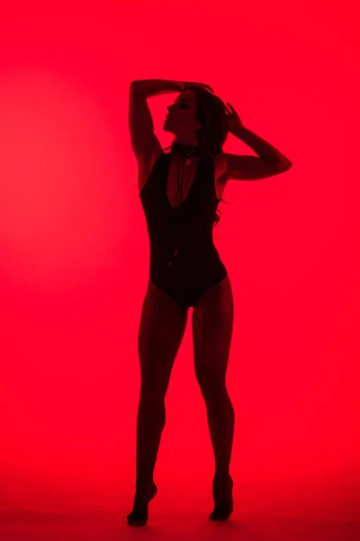 Silhouette of beautiful sexy young woman, isolated on red — Stock Photo