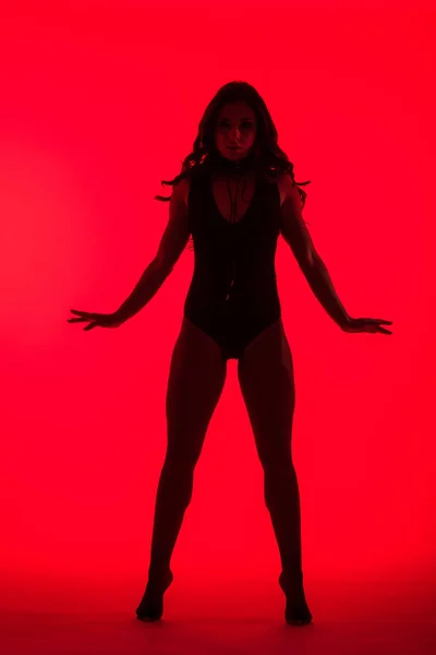 Silhouette einer schönen, verführerischen jungen Frau, isoliert auf Rot — Stockfoto