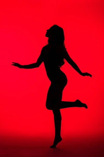 Black silhouette of sensual woman on red — Stock Photo