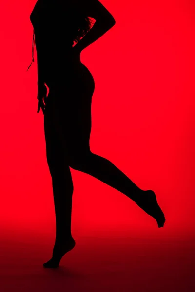 Silhouette nera di donna sexy in posa sul rosso — Foto stock