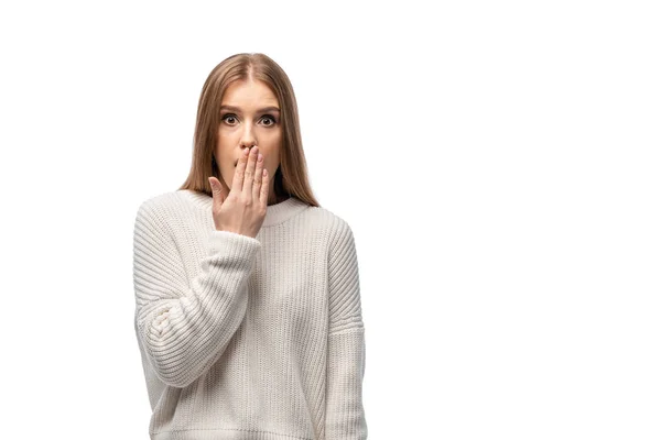 Attraktive schockierte junge Frau in weißem Pullover, der den Mund bedeckt, isoliert auf weißem Grund — Stockfoto