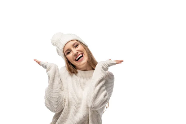 Взволнованная молодая женщина с жест пожатия плечами в белом трикотажном свитере и шляпе, изолированные на белом — стоковое фото