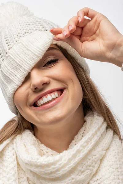 Attraktives, fröhliches Mädchen mit weißer Strickmütze, das in die Kamera blickt, isoliert auf weiss — Stockfoto