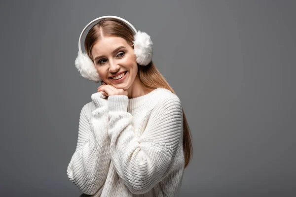 Femme souriante posant en pull blanc et chauffe-oreilles, isolée sur gris — Photo de stock