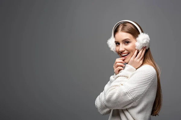 Приваблива збуджена дівчина позує в білому светрі і вухах, ізольована на сірому — стокове фото