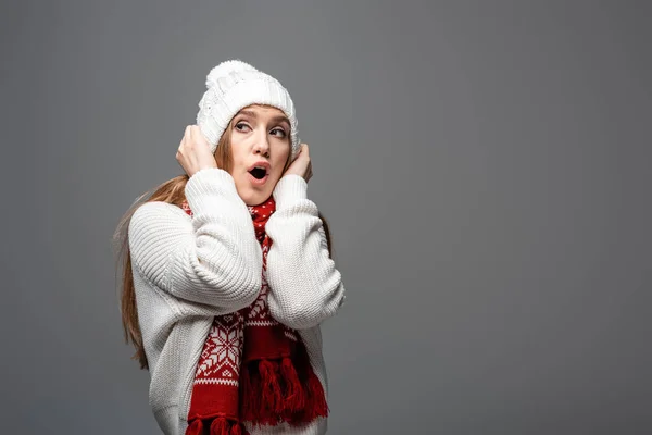 Attractive surprised girl in knitted hat and scarf, isolated on grey — Stock Photo