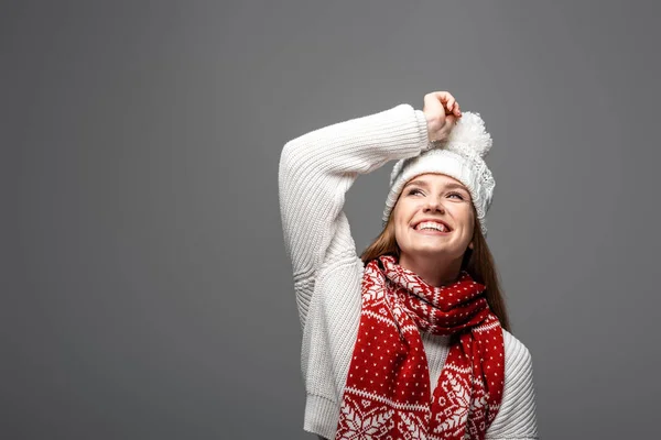 Привлекательная улыбающаяся женщина в вязаной шляпе и шарфе, изолированная на сером — стоковое фото