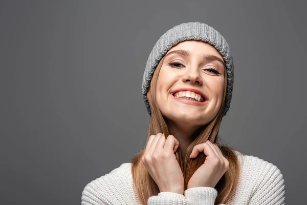 Привлекательная улыбающаяся девушка в вязаной шляпе и свитере, изолированная на сером — стоковое фото