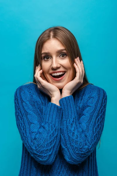 Attractive excited woman in blue knitted sweater, isolated on blue — Stock Photo