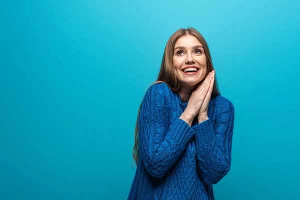 Mulher feliz atraente que deseja em camisola de malha azul, isolado em azul — Fotografia de Stock