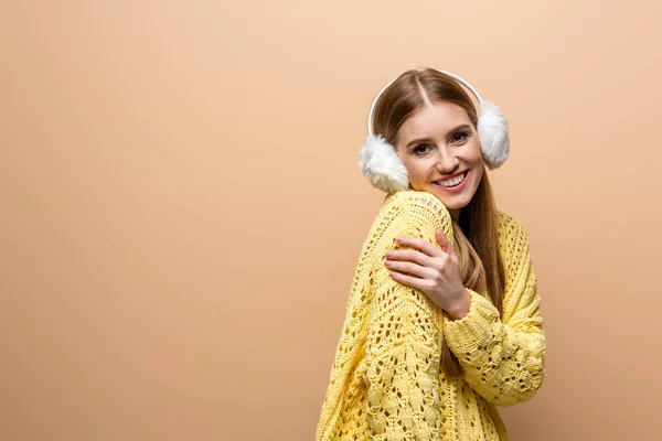 Bella donna fredda in maglione giallo e scalda orecchie, isolata su beige — Foto stock