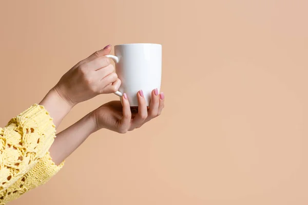 Partial view of woman in yellow sweater holding cup of coffee, isolated on beige — Stock Photo