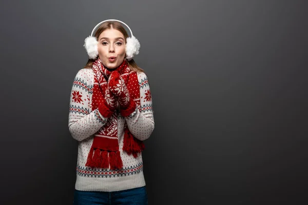 Überraschte Frau in Weihnachtspullover, Schal, Handschuhe und Ohrenschützer, isoliert auf grau — Stockfoto