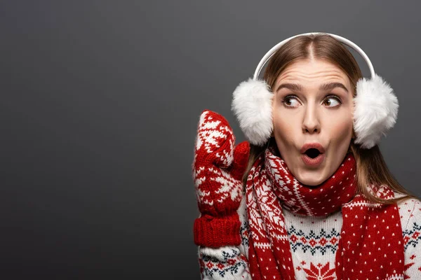 Mujer excitada en jersey de Navidad, bufanda, manoplas y orejeras, aislada en gris — Stock Photo