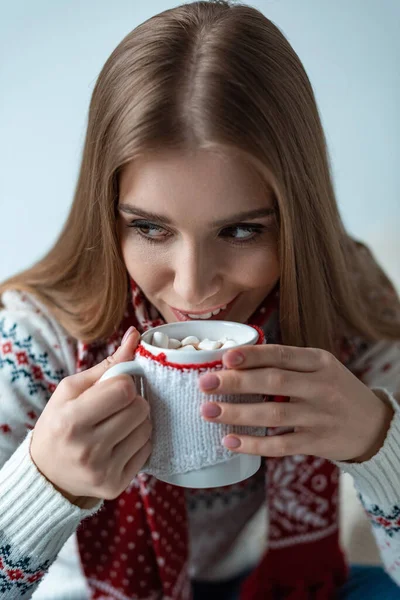 Attractive woman drinking cocoa with marshmallow, isolated on grey — Stock Photo