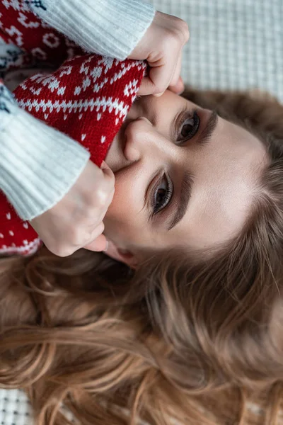 Attraktive Frau in warmem Pullover und Schal auf Decke liegend — Stockfoto