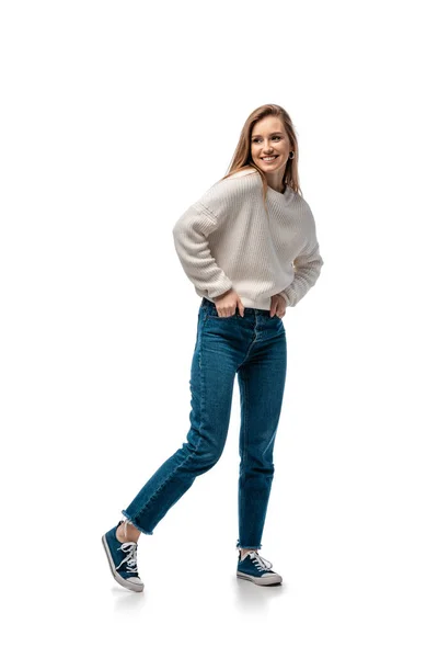 Красива усміхнена жінка в джинсах і білому светрі, ізольована на білому — стокове фото