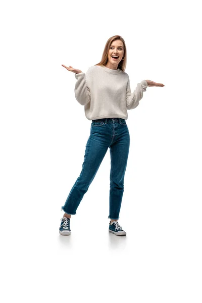 Atractiva mujer excitada en jeans y suéter blanco posando con gesto de encogimiento, aislado en gesto blanco - foto de stock